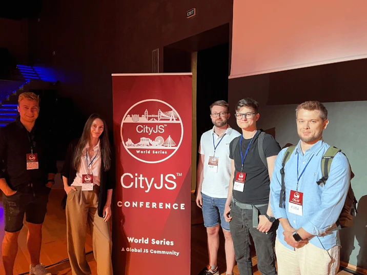 Uczestnicy konferencji CityJS pozują przy banerze wydarzenia w przestrzeni eventowej