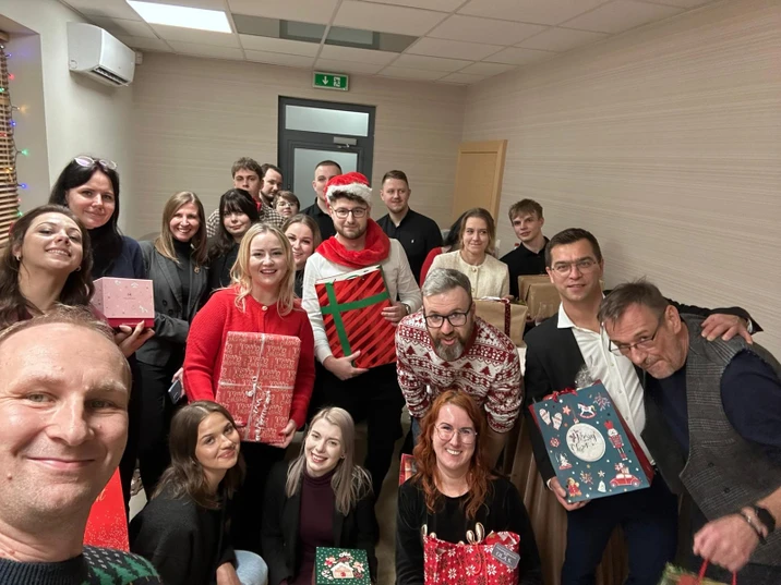 Grupa pracowników podczas firmowej świątecznej zabawy z prezentami i uśmiechami w biurze