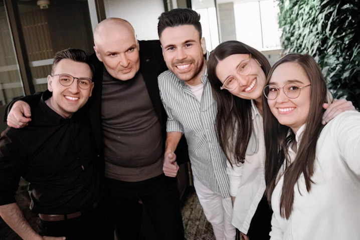 Pięć uśmiechniętych osób w biurze pozujących razem na zdjęcie w przyjaznej atmosferze