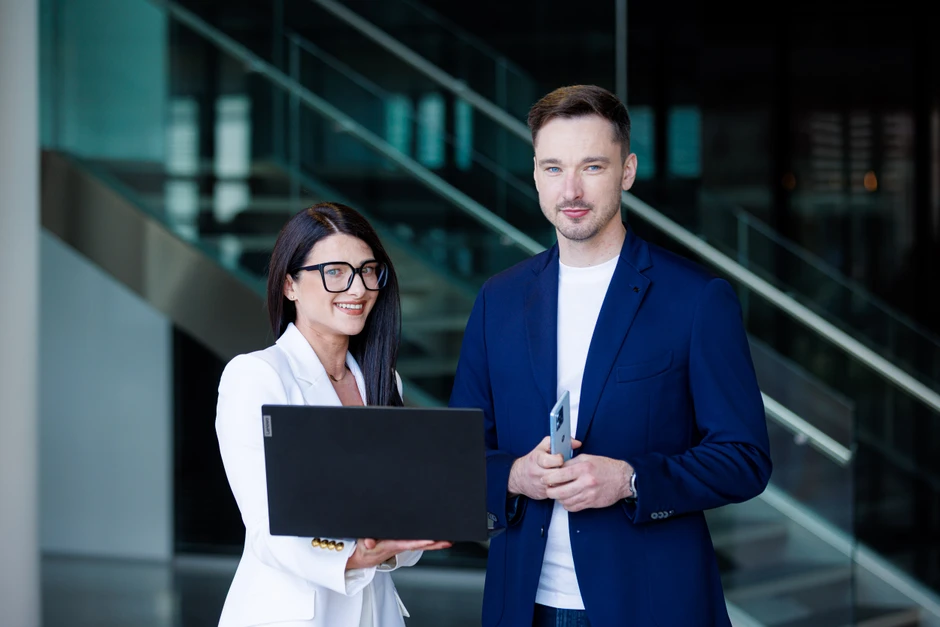 Dwójka profesjonalistów w nowoczesnym biurze pracuje razem, trzymając laptop i telefon