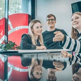 Grupa młodych osób rozmawia i uśmiecha się podczas spotkania w nowoczesnym biurze