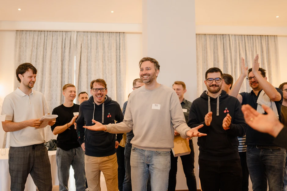 Grupa mężczyzn w nieformalnej atmosferze świętuje sukces podczas firmowego spotkania w jasnym pomieszczeniu