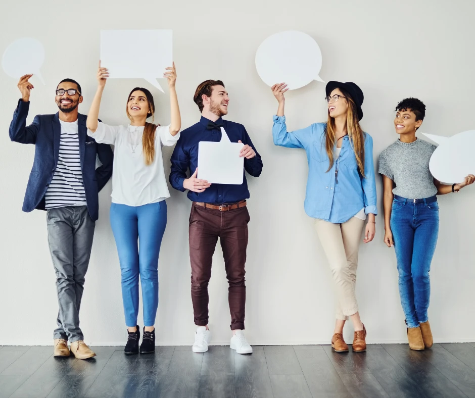 Zespół pięciu różnorodnych pracowników trzyma puste dymki rozmów na jasnym tle biura