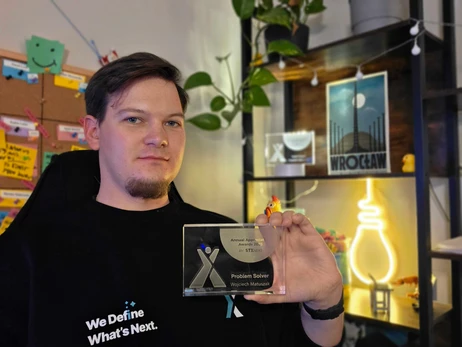 Pracownik firmy prezentuje nagrodę Problem Solver w nowoczesnym biurze z dekoracjami i planszą z zadaniami