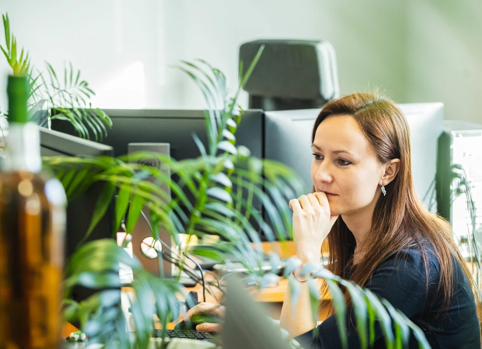 Kobieta pracująca przy komputerze w zielonym i nowoczesnym biurze pełnym roślin