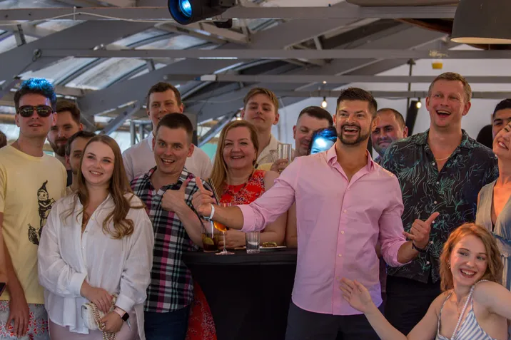 Grupa uśmiechniętych pracowników podczas firmowego eventu w nowoczesnym, jasno oświetlonym wnętrzu