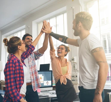 Zespół młodych pracowników w biurze świętuje sukces podczas burzy mózgów z uśmiechem