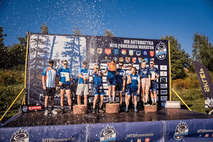 Zespół zawodników na podium z nagrodami podczas MTB Pomerania Maraton w słoneczny dzień