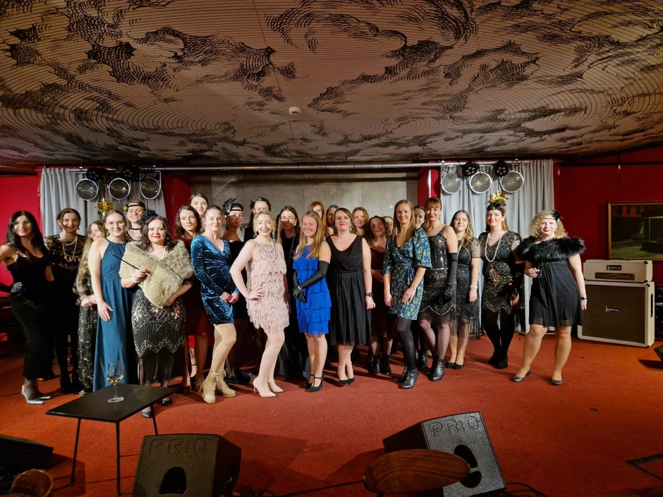 Grupa kobiet w stylizacjach retro na firmowym wydarzeniu w eleganckim wnętrzu z artystycznym sufitem