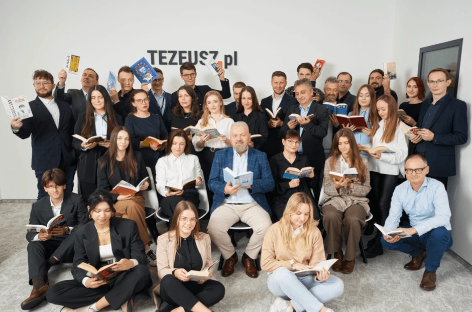 Zespół Tezeusz.pl pozuje z książkami w nowoczesnym biurze, promując czytelnictwo i edukację