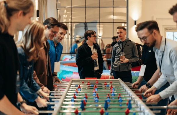 Pracownicy firmy rywalizują przy piłkarzykach podczas integracyjnego spotkania w biurze