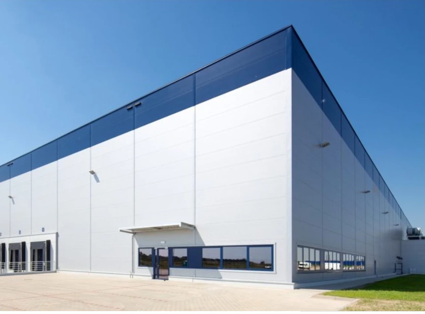 Nowoczesny magazyn lub centrum dystrybucji z dużymi bramami i jasnym oświetleniem zewnętrznym