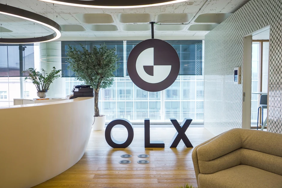 Nowoczesne biuro z logo OLX, wygodną kanapą i naturalnymi roślinami przy recepcji