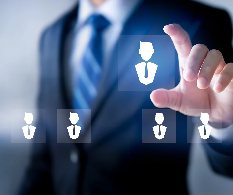 Biznesmen w garniturze wybiera kandydatów na tle graficznych ikon symbolizujących pracowników