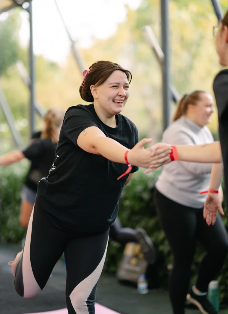 Kobieta uśmiecha się podczas ćwiczeń grupowych na sali fitness w przyjaznej atmosferze