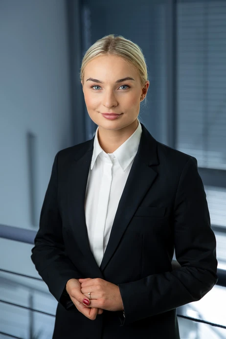 Profesjonalna kobieta w garniturze z białą koszulą pozująca w nowoczesnym biurze