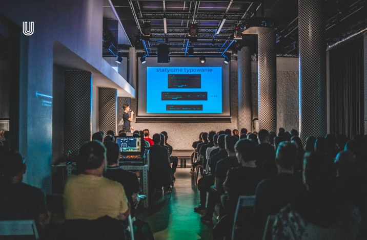 Prezentacja o statycznym typowaniu na konferencji programistycznej z liczną widownią w nowoczesnej sali