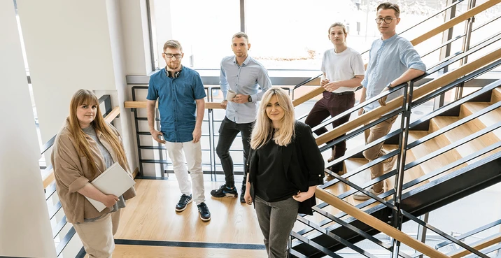 Zespół młodych profesjonalistów spotyka się na klatce schodowej w nowoczesnym biurze firmy