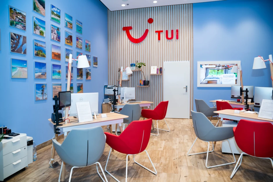 Nowoczesne biuro TUI z jasnoniebieskimi ścianami i zdjęciami wakacyjnych destynacji na ścianie