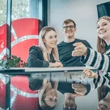 Grupa młodych ludzi rozmawia i uśmiecha się podczas spotkania w nowoczesnym biurze