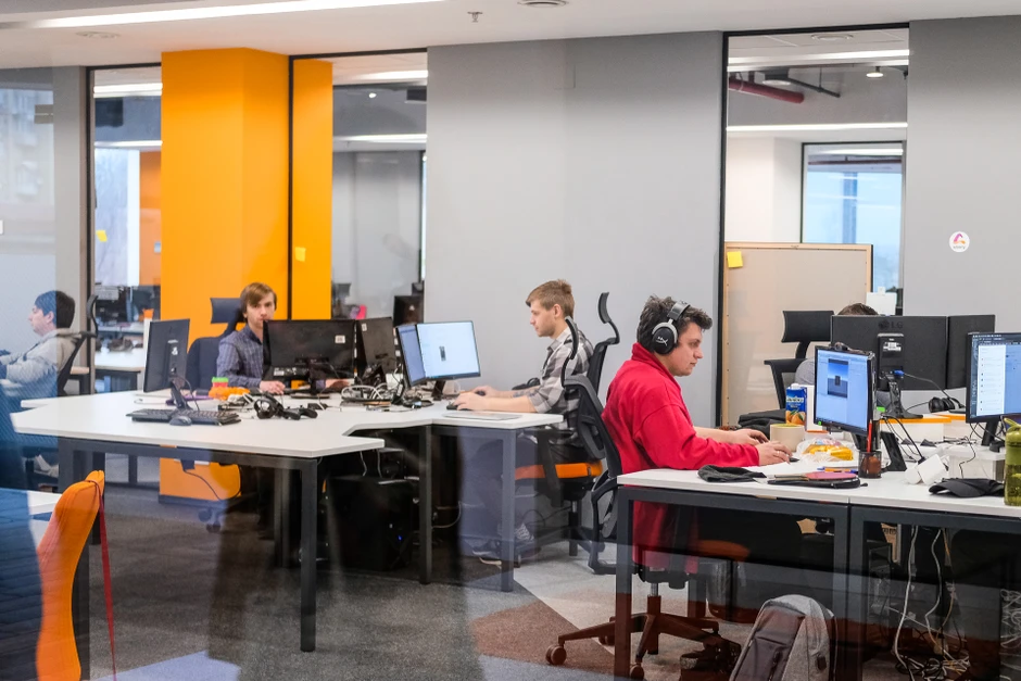 Pracownicy w nowoczesnym biurze skupieni na pracy przy komputerach w jasnym open space