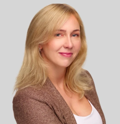 Portret uśmiechniętej kobiety o blond włosach w eleganckim brązowym swetrze na jasnym tle
