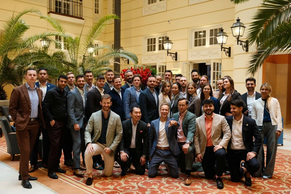 Grupa profesjonalistów w eleganckim otoczeniu hotelowego lobby pozujących do zdjęcia zespołowego