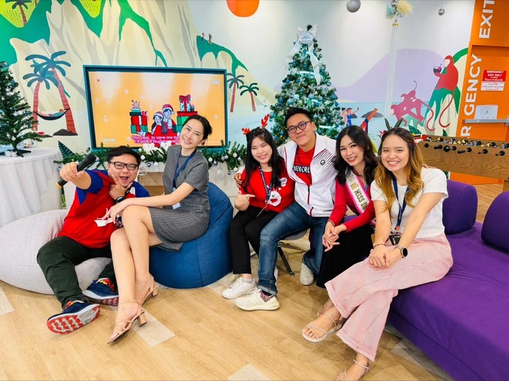 Zespół pracowników w świątecznych dekoracjach relaksuje się w przyjaznym biurze z kolorowymi meblami