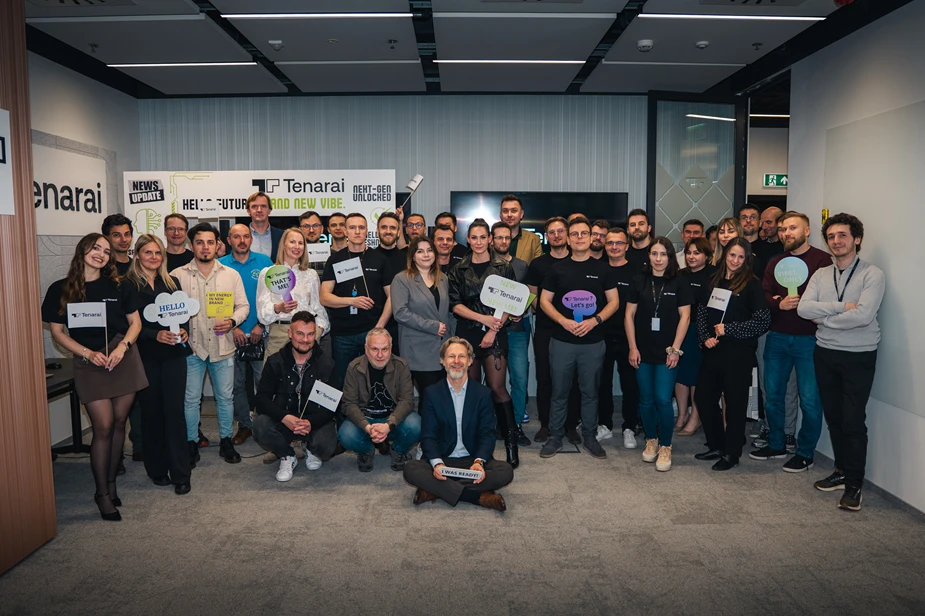 Zespół pracowników firmy Tenarai na wspólnym zdjęciu w nowoczesnym biurze z uśmiechami i transparentami