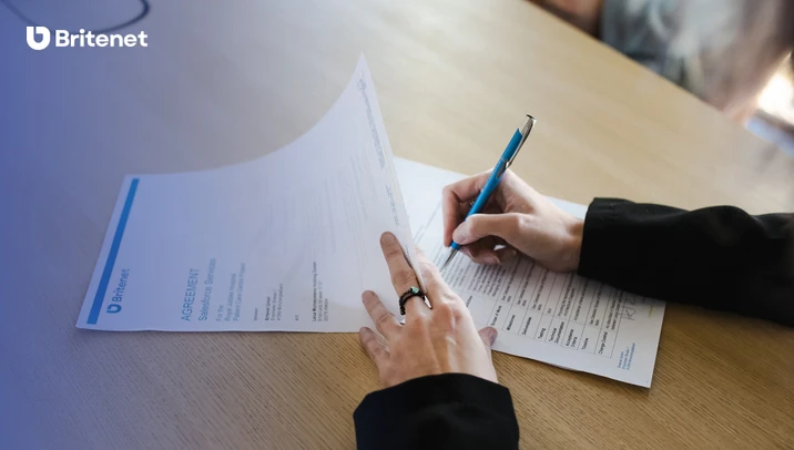 Osoba podpisująca umowę Salesforce Services przy drewnianym biurku w firmie Britenet