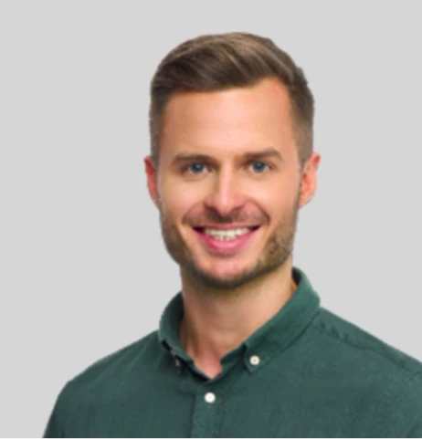 Portret uśmiechniętego mężczyzny w zielonej koszuli na jasnym, neutralnym tle