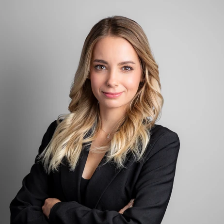 Młoda kobieta z rozpuszczonym blond włosami w czarnej marynarce na jasnym tle w profesjonalnym ujęciu