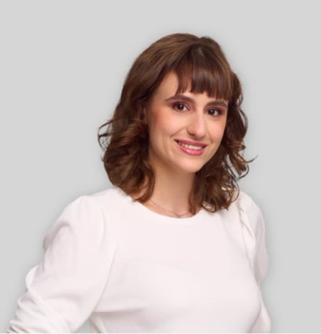 Młoda kobieta w białej bluzce z uśmiechem na twarzy na jasnym tle w profilu pracodawcy