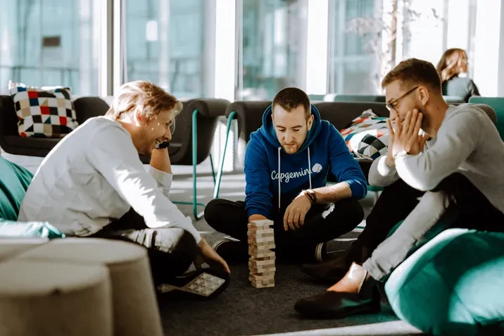 Trzech młodych mężczyzn gra w biurze w grę wieżową, relaksując się podczas przerwy w pracy
