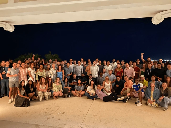 Duża grupa pracowników pozująca razem na zewnątrz nocą podczas firmowego spotkania integracyjnego