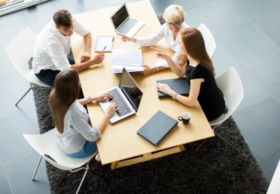 Cztery osoby dyskutujące przy stole w nowoczesnym biurze podczas spotkania zespołowego