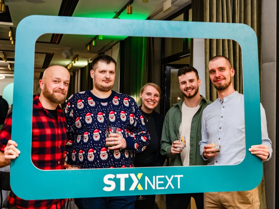 Grupa pracowników STX Next pozująca z napojami w ramce na firmowym wydarzeniu integracyjnym