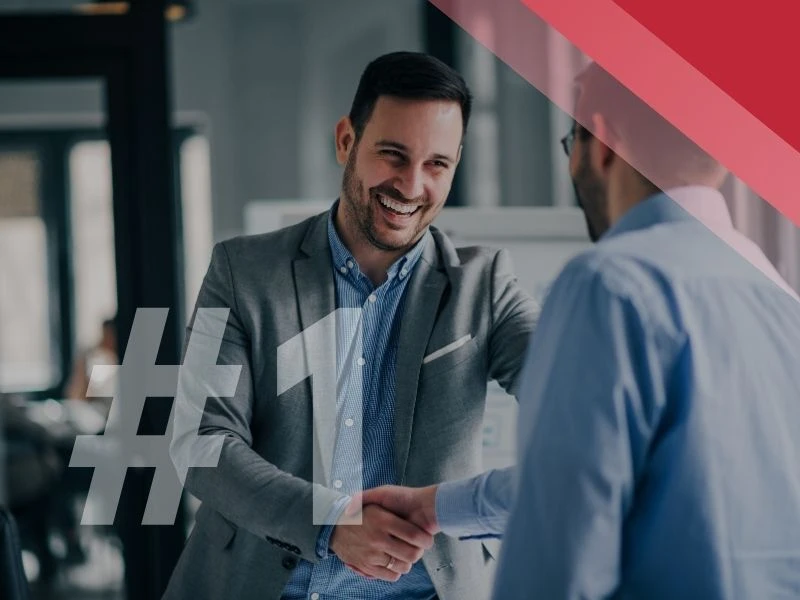 Dwóch mężczyzn uśmiecha się i podaje sobie ręce w nowoczesnym biurze podczas spotkania biznesowego