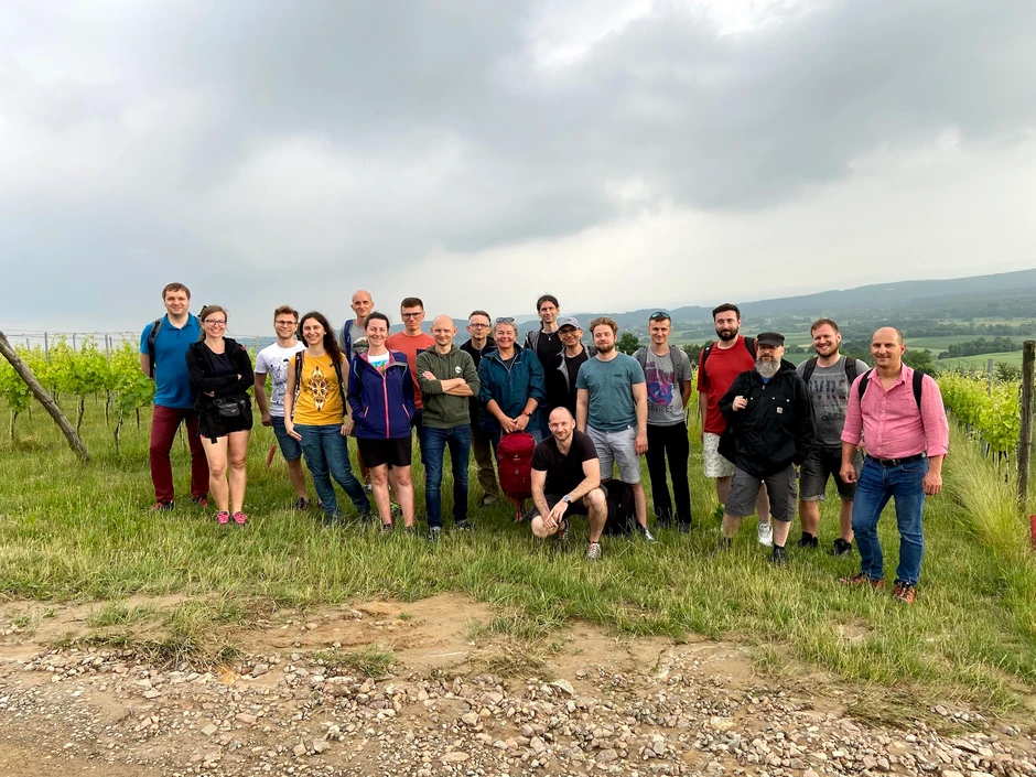 Grupa pracowników podczas wycieczki integracyjnej wśród zielonych wzgórz i winnic pod pochmurnym niebem