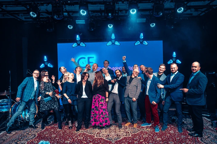 Zespół firmy pozuje razem na scenie podczas firmowego wydarzenia, panuje wesoła atmosfera