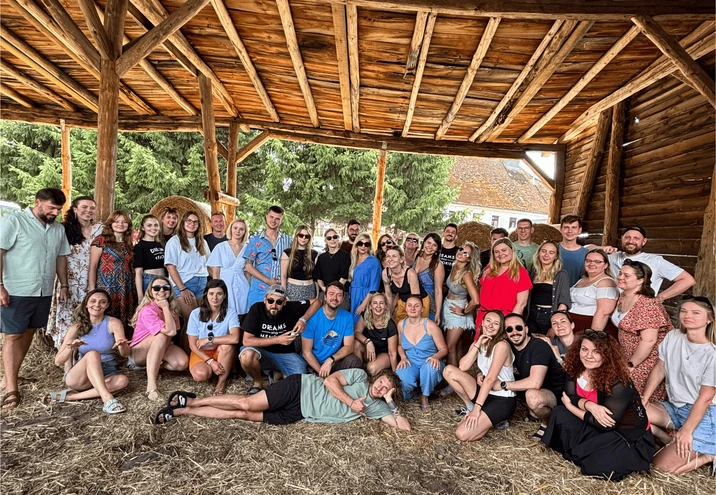 Grupa młodych pracowników podczas integracyjnego spotkania w drewnianej altanie na łonie natury