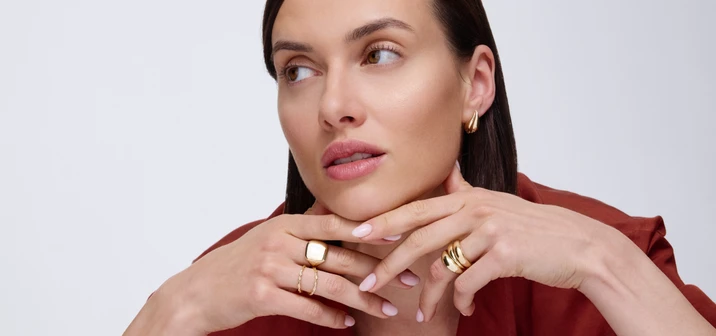 Portret eleganckiej kobiety z biżuterią ze złota w modnym stylu i brązowej stylizacji