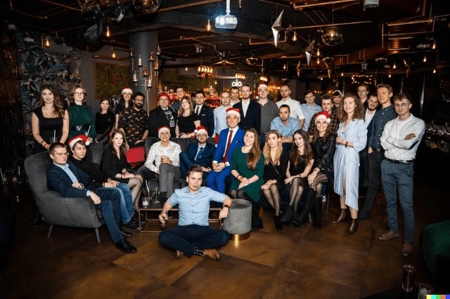 Zespół firmy podczas świątecznego spotkania z uśmiechami i czapkami Mikołaja w przytulnym wnętrzu