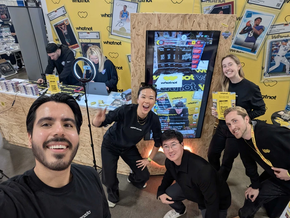 Zespół pracowników firmy whatnot pozujący uśmiechnięci na tle stoiska wystawowego podczas wydarzenia