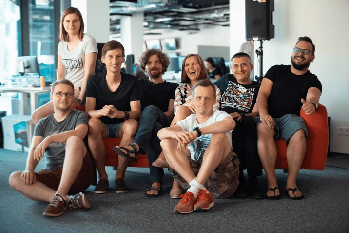 Zespół pracowników w biurze siedzi razem na kanapie i podłodze, uśmiechnięci i zrelaksowani