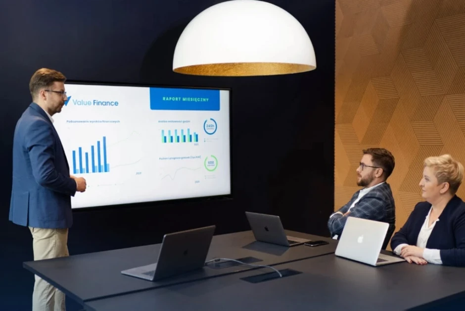 Spotkanie biznesowe w nowoczesnej sali konferencyjnej z prezentacją danych finansowych na ekranie