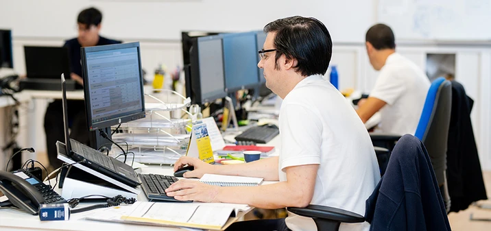 Pracownicy w biurze skupieni na pracy przy komputerach w nowoczesnym środowisku biurowym