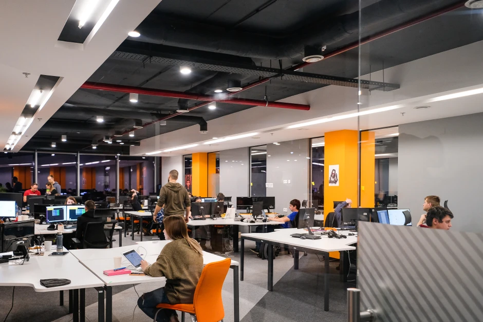 Nowoczesne biuro z pomarańczowymi akcentami, w którym pracownicy intensywnie korzystają z komputerów