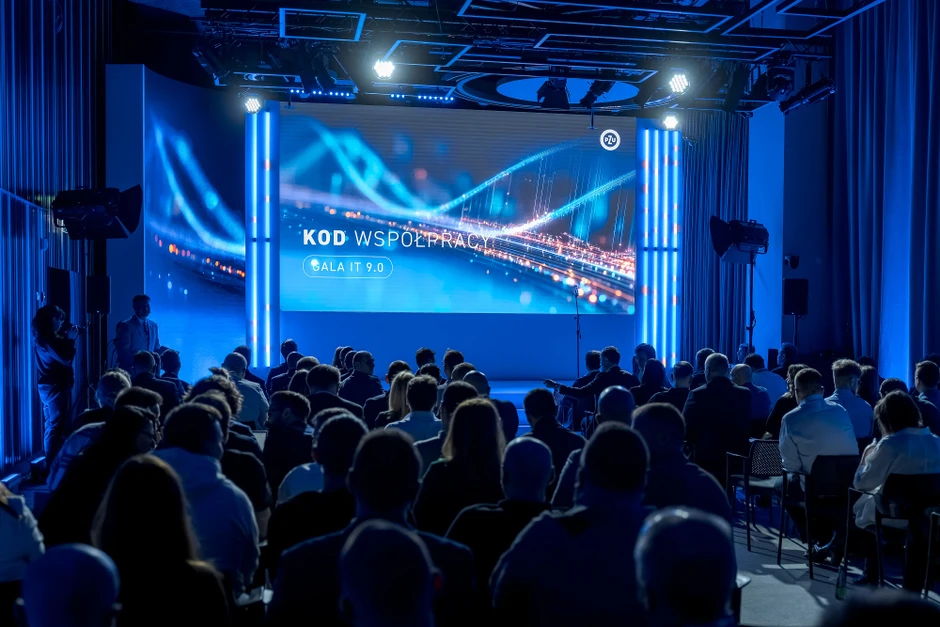 Uczestnicy na konferencji IT Gala 9.0 podczas prezentacji z niebieskim oświetleniem i ekranem