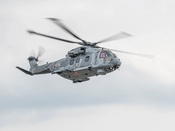 Szary wojskowy śmigłowiec w locie na tle jasnego nieba w nowoczesnym wyposażeniu